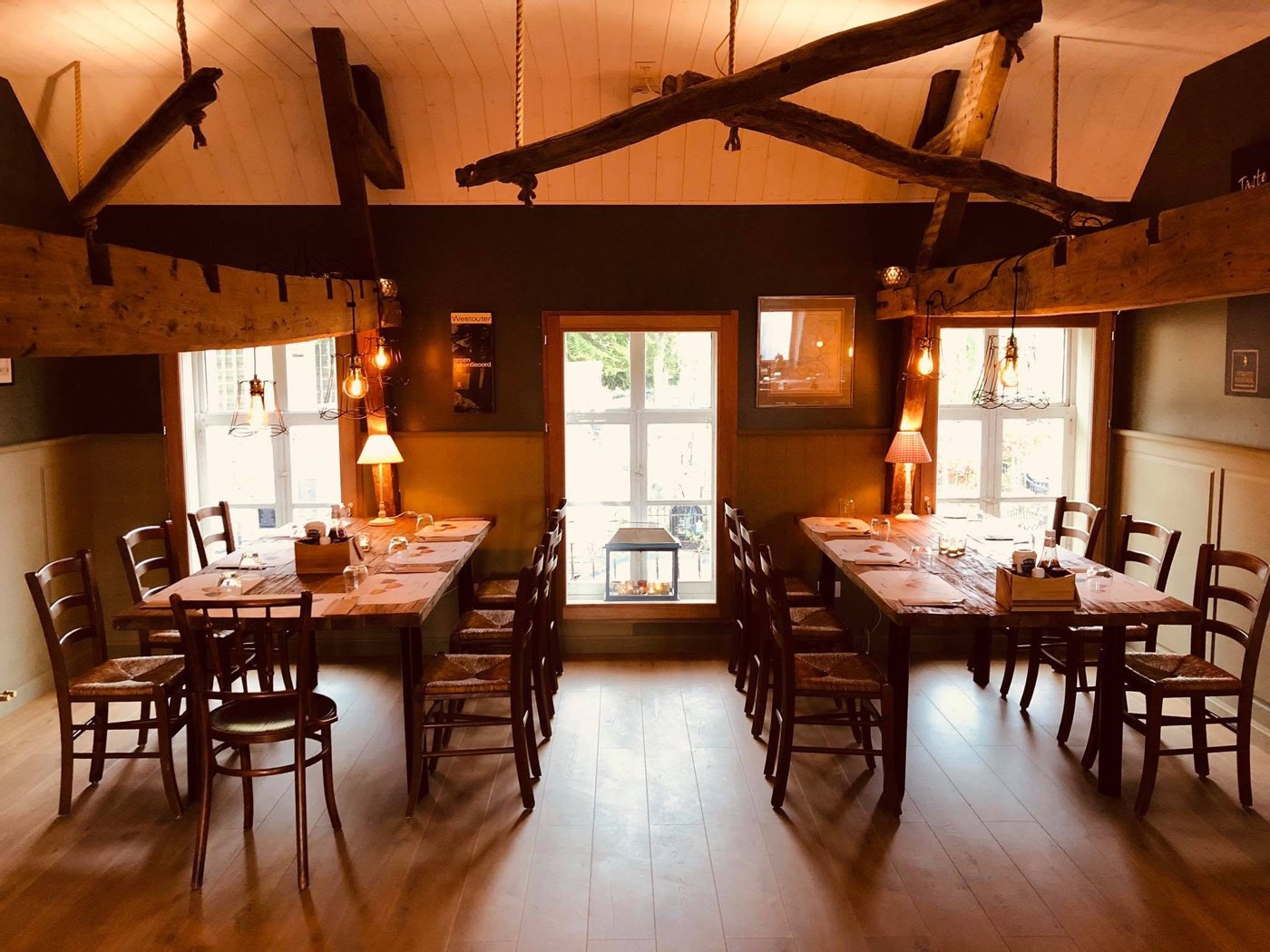 The room upstairs with two long wooden tables and large windows