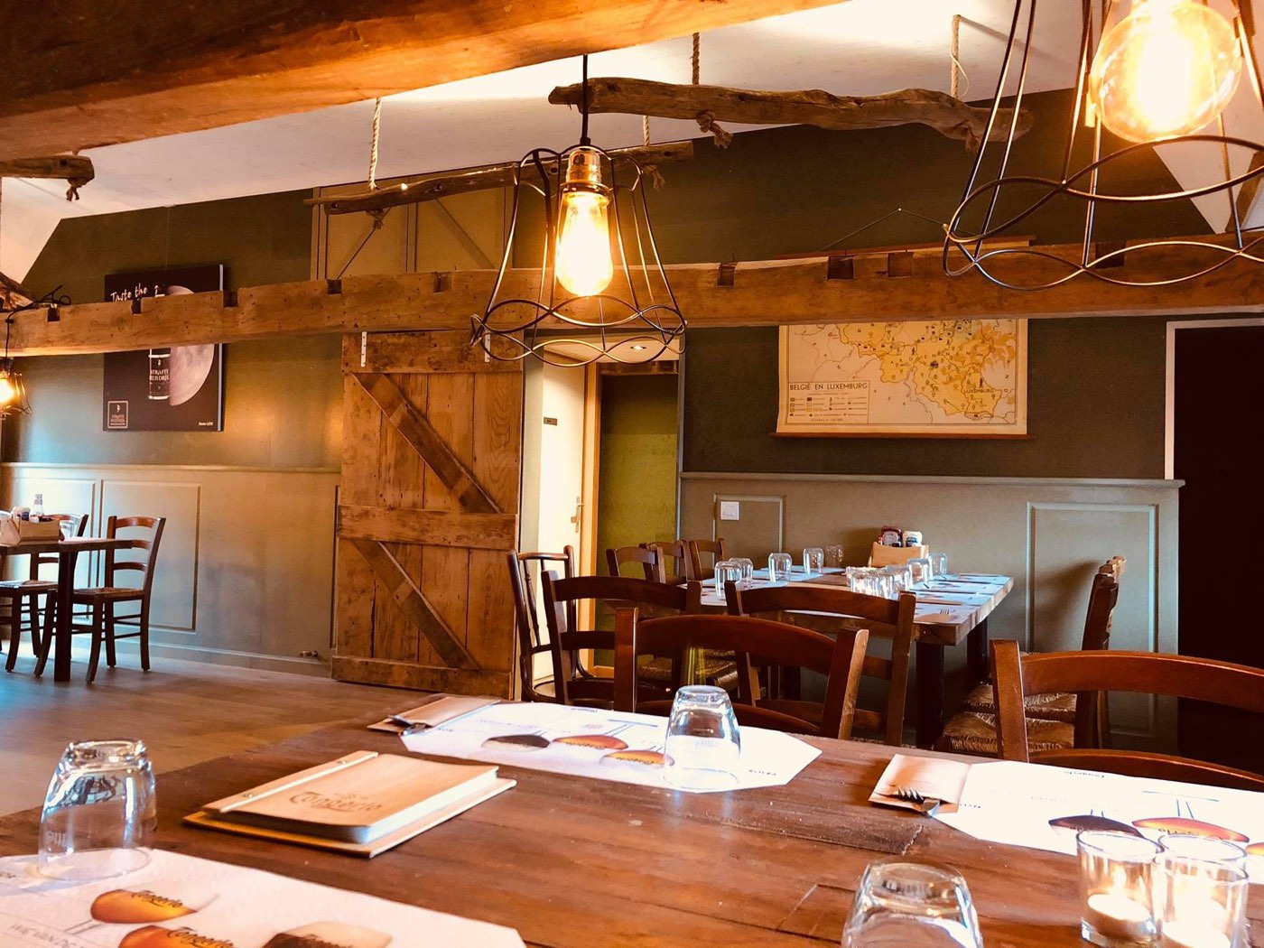 View across the room upstairs with a reclaimed-wood sliding door and hanging lamps